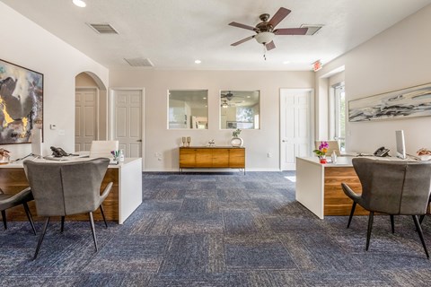 a living room with chairs and a desk and a ceiling fan