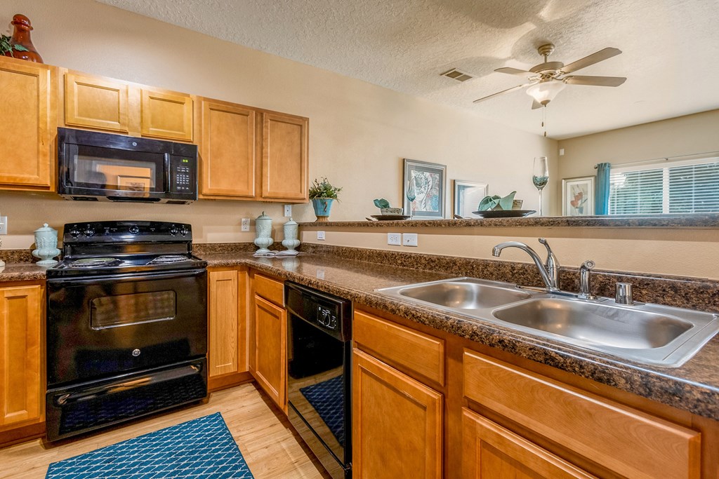 a kitchen with a sink and a stove and a ceiling fan