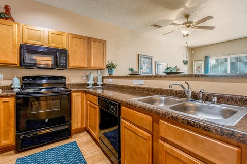 a kitchen with a sink and a stove and a ceiling fan