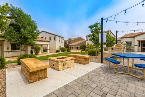 the backyard has a picnic table and benches and a fire pit