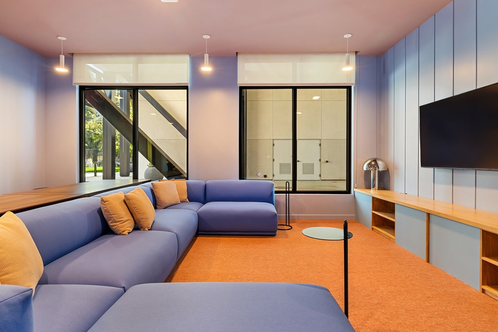 A blue couch with orange pillows in a room with a television.