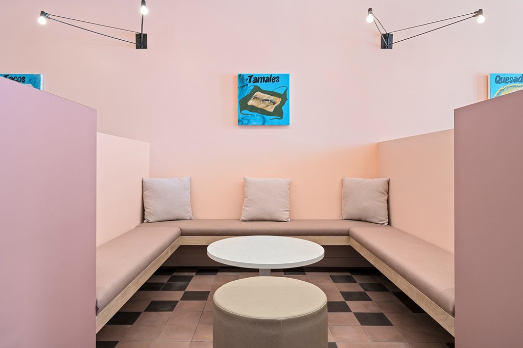 A room with a pink wall and a white table in the middle.