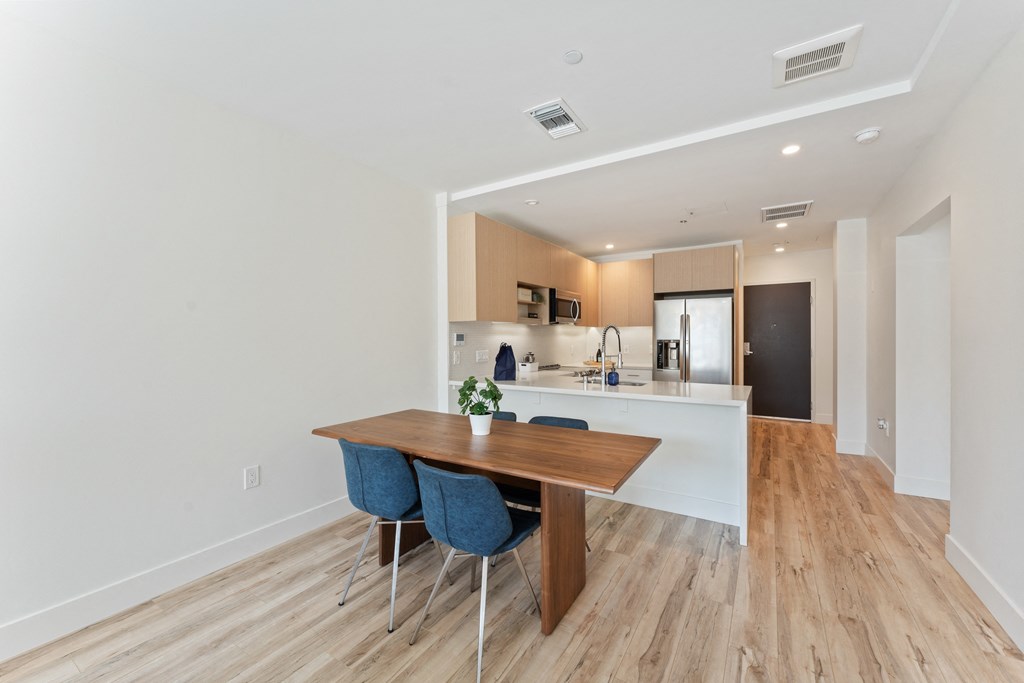 a dining room with a wooden table and chairs in front of a kitchen