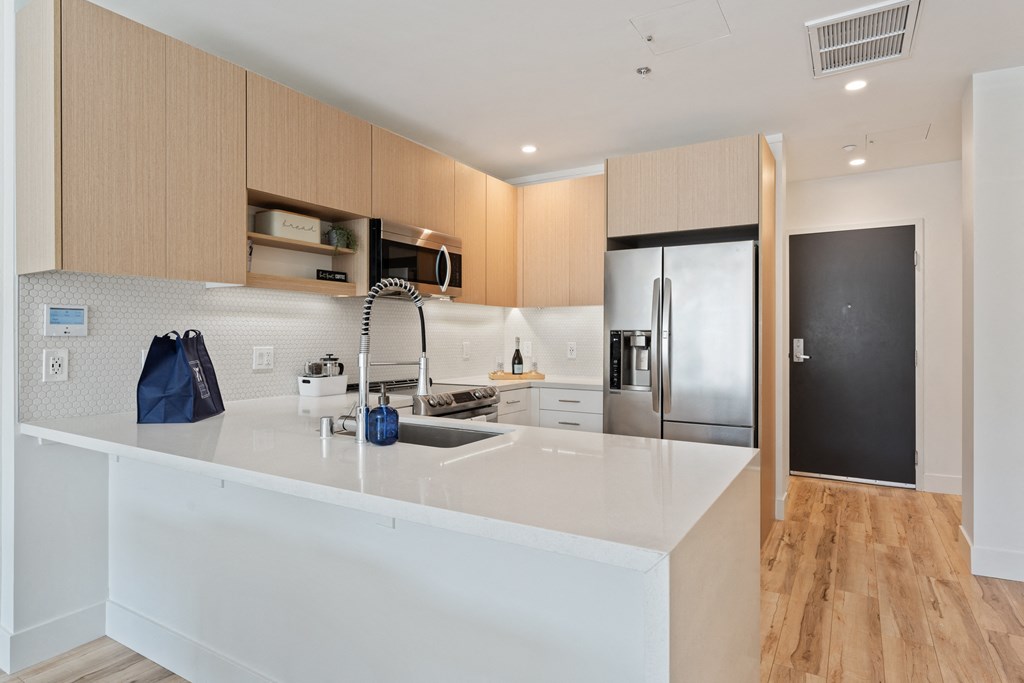 a kitchen with a white counter top and a stainless steel refrigerator