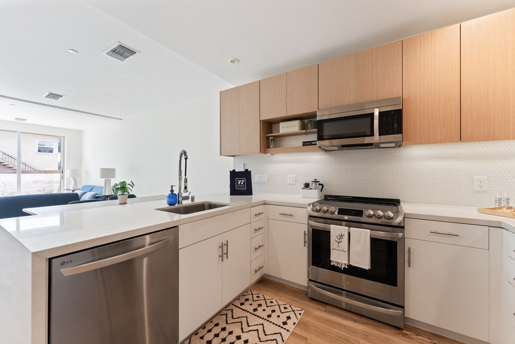 an apartment kitchen with stainless steel appliances and wooden cabinets