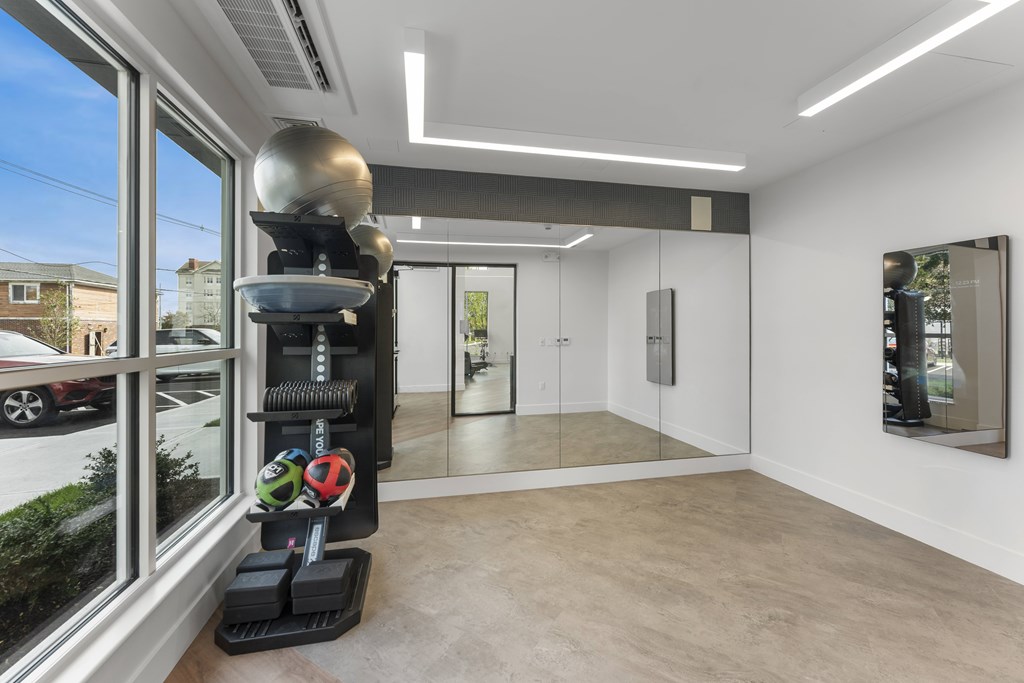 A room with a large window, a treadmill, and a mirror on the wall.