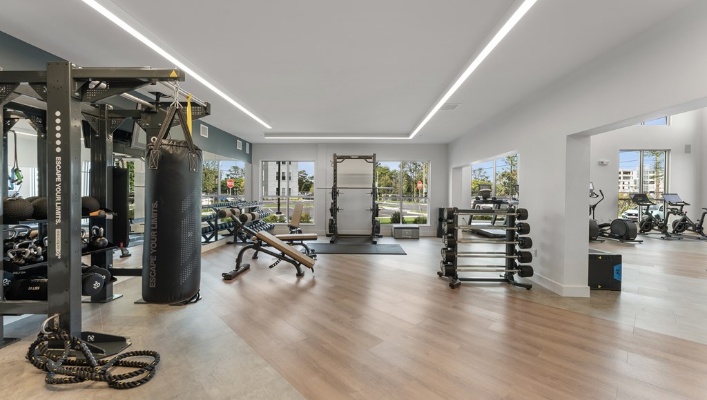 A gym with a variety of equipment including a punching bag, weights, and exercise machines.