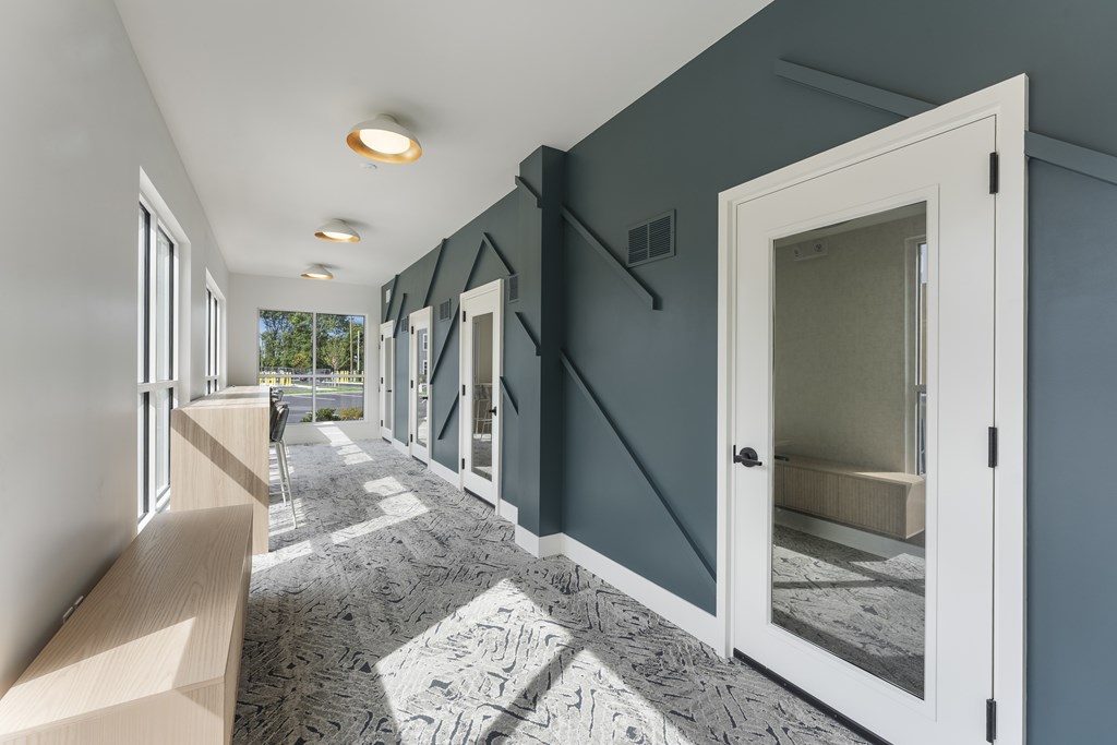 A hallway with a carpeted floor and white doors.