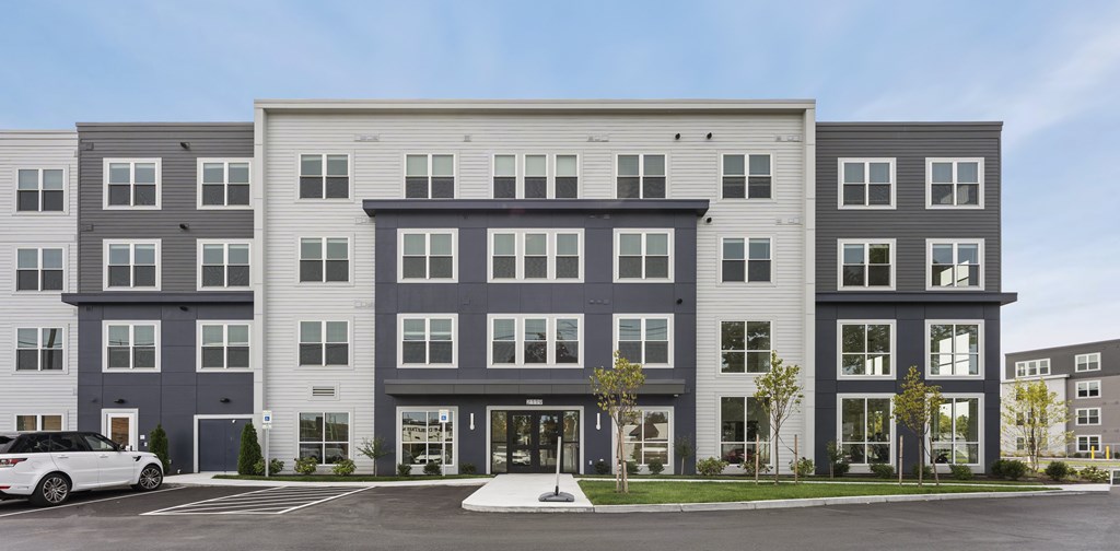 A modern apartment building with a white car parked in front.