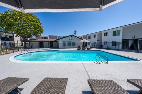 A swimming pool surrounded by lounge chairs and trees.