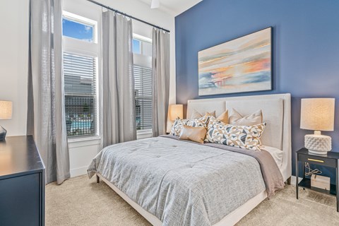 A bedroom with a large bed and a painting on the wall.