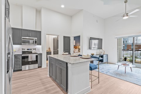 A modern kitchen with a large island and a refrigerator on the left.