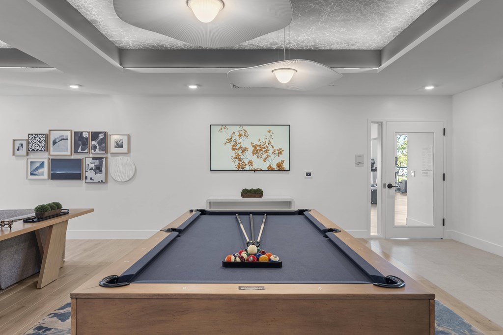 A pool table is in the middle of a room with a light hanging from the ceiling.