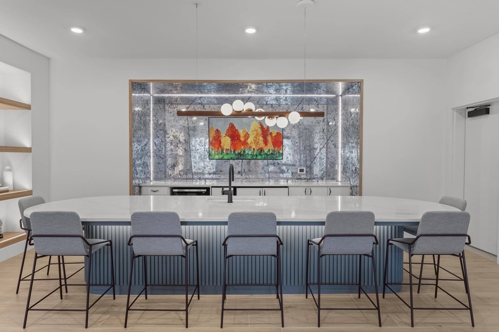 A modern kitchen with a large island and grey chairs.