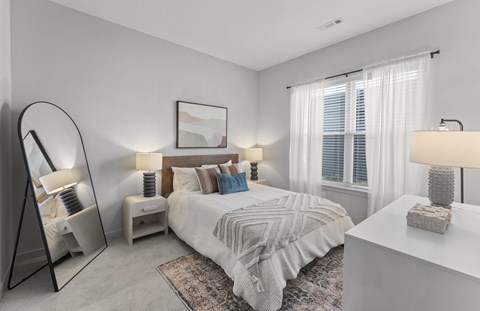 A bedroom with a large bed, a side table with a lamp, and a mirror.