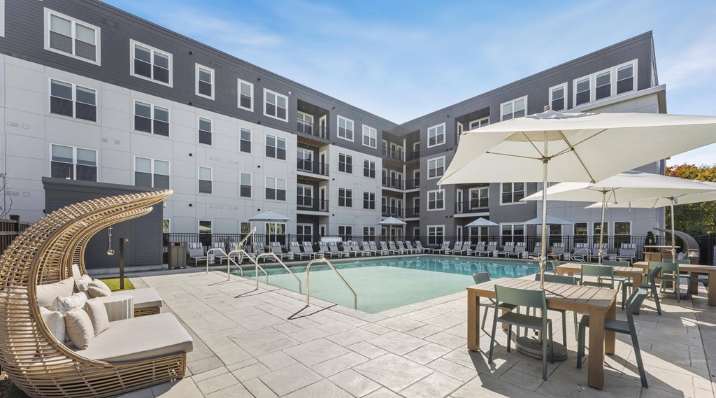 A large white umbrella is shading a table and chairs on a patio.