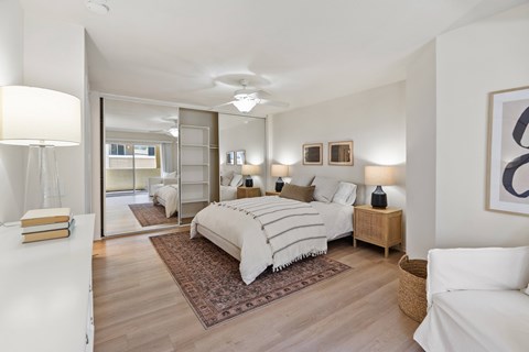 A bedroom with a large bed and a mirror on the wall.