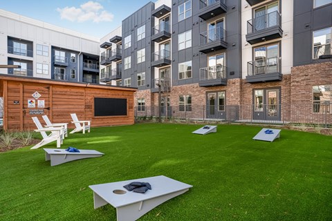 A modern outdoor movie theater area with white chairs and a black screen.