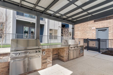 A patio with a grill and a wall made of bricks.