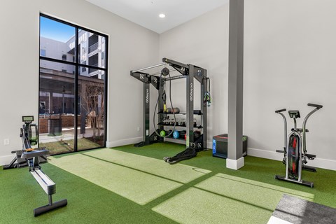 A home gym with a green carpet and various exercise equipment.