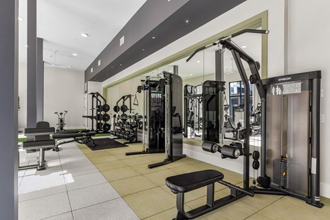 A gym with a variety of equipment including a squat rack, a leg press machine, and a bench.