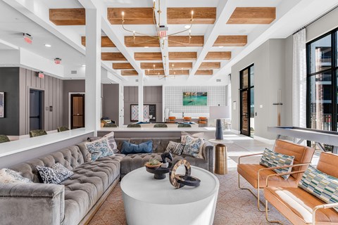 A modern living room with a grey sofa and a wooden ceiling.