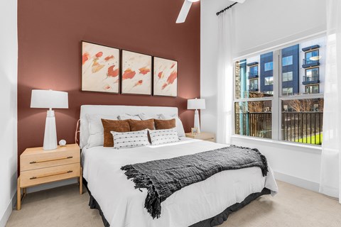 A bedroom with a large bed and a window overlooking a balcony.