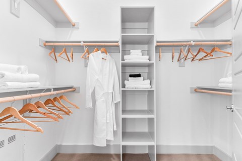 A white bathroom with a white robe hanging on a rack.