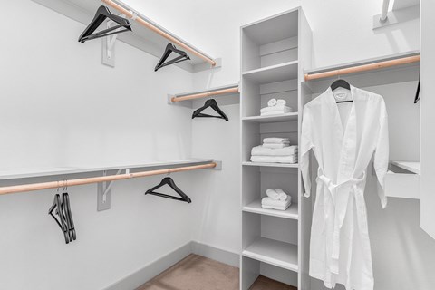 A white bathrobe is hanging on a rack in a white bathroom.