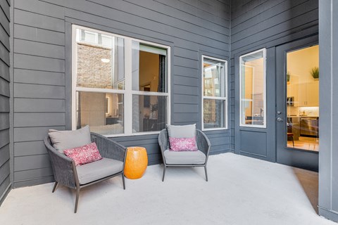 Two grey chairs with pink cushions are placed on a grey floor.