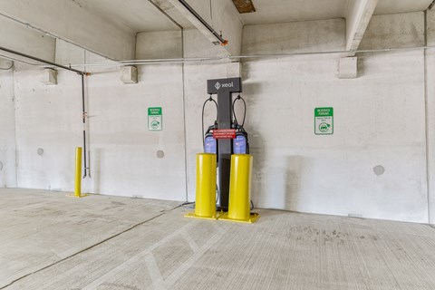 A yellow and black fuel pump is in a concrete room with a green sign on the wall.