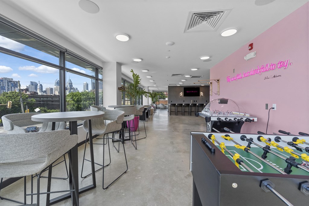 a room with a foosball table and tables with chairs
