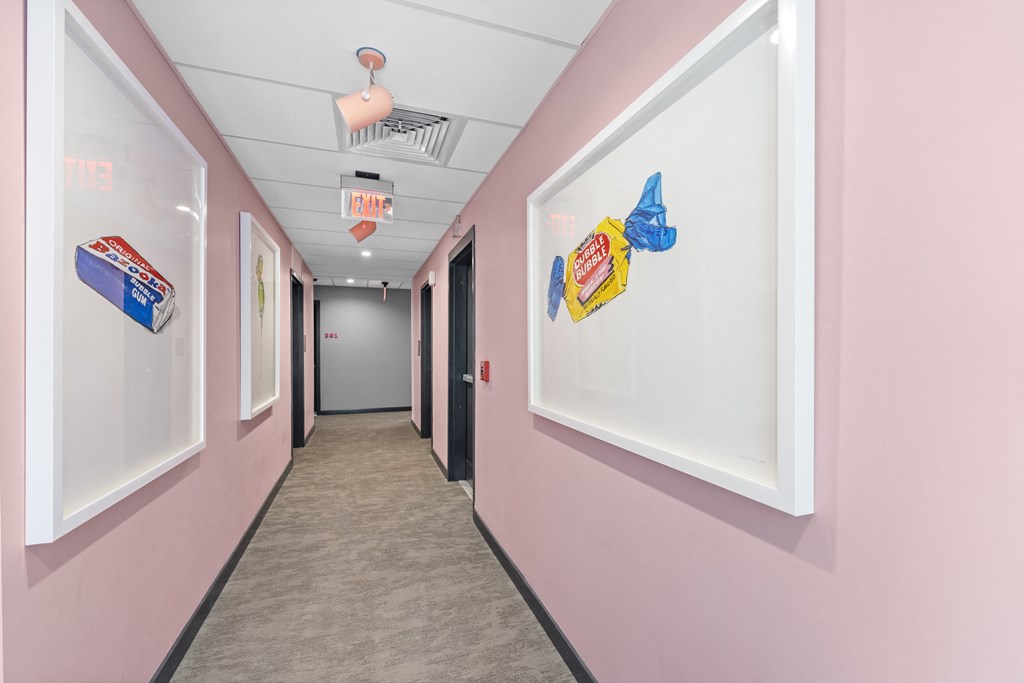 a long corridor with pink walls and white frames on the wall