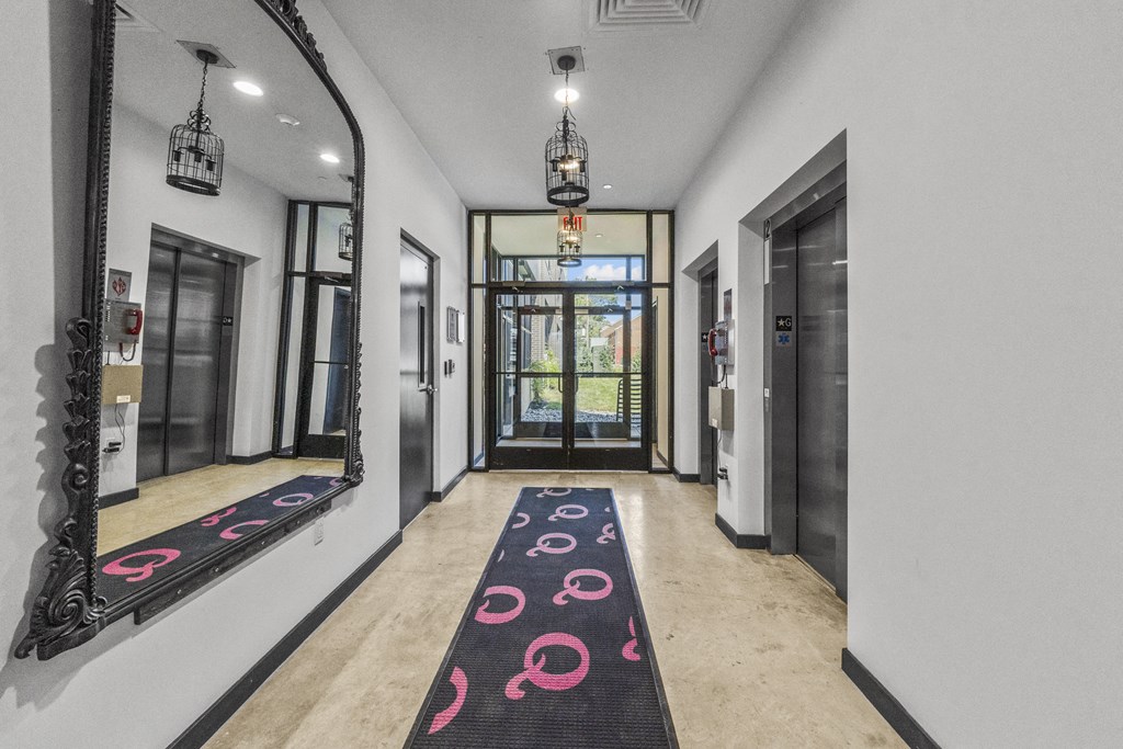 a long corridor with doors and a carpet with pink circles on it