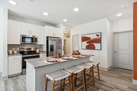 a kitchen with white cabinets and a counter top with bar stools