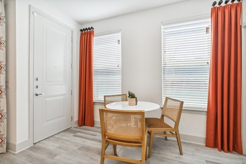 a dining room with a table and chairs and two windows