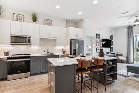 an open kitchen and dining area with stainless steel appliances and white cabinets