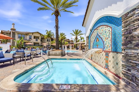 A pool with a blue tiled wall and a palm tree in the background.