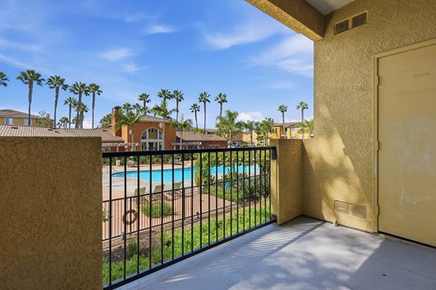 A balcony with a pool and palm trees in the background.