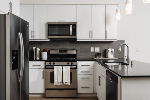 A modern kitchen with a black refrigerator and white cabinets.