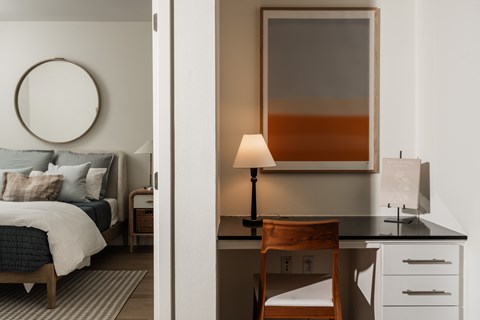 A bedroom with a bed, desk, and chair.