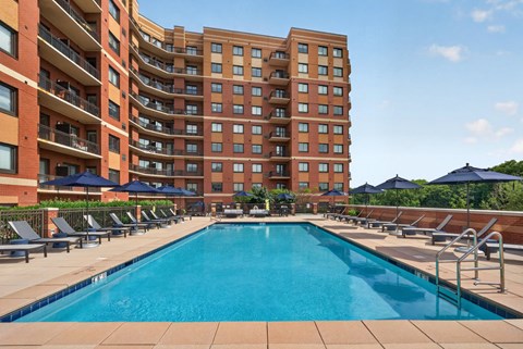 A large swimming pool in front of a multi-story apartment building.
