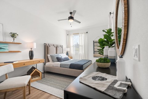 a bedroom with a bed and a desk and a ceiling fan