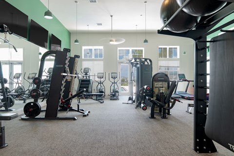 A gym with a variety of equipment including treadmills, weights, and exercise machines.