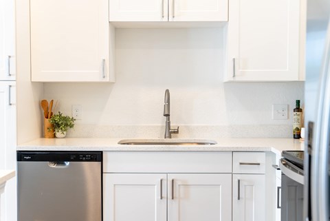 A kitchen with white cabinets and a stainless steel dishwasher.
