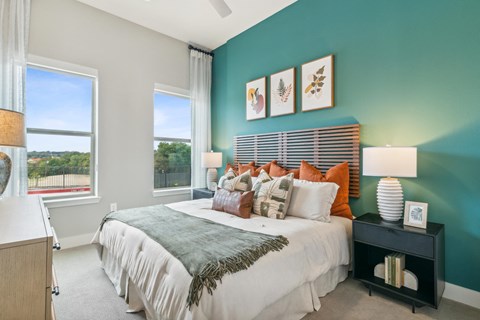 a bedroom with a large bed and two windows