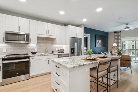 A modern kitchen with white cabinets and a marble countertop.