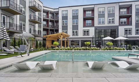 A pool area with a wooden structure in front of apartment buildings.
