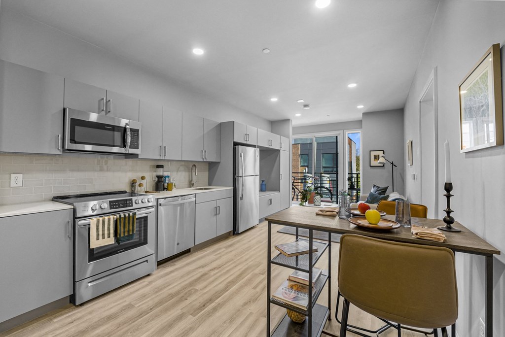 a kitchen with white cabinetry and stainless steel appliances and a wooden table with yellow chairs