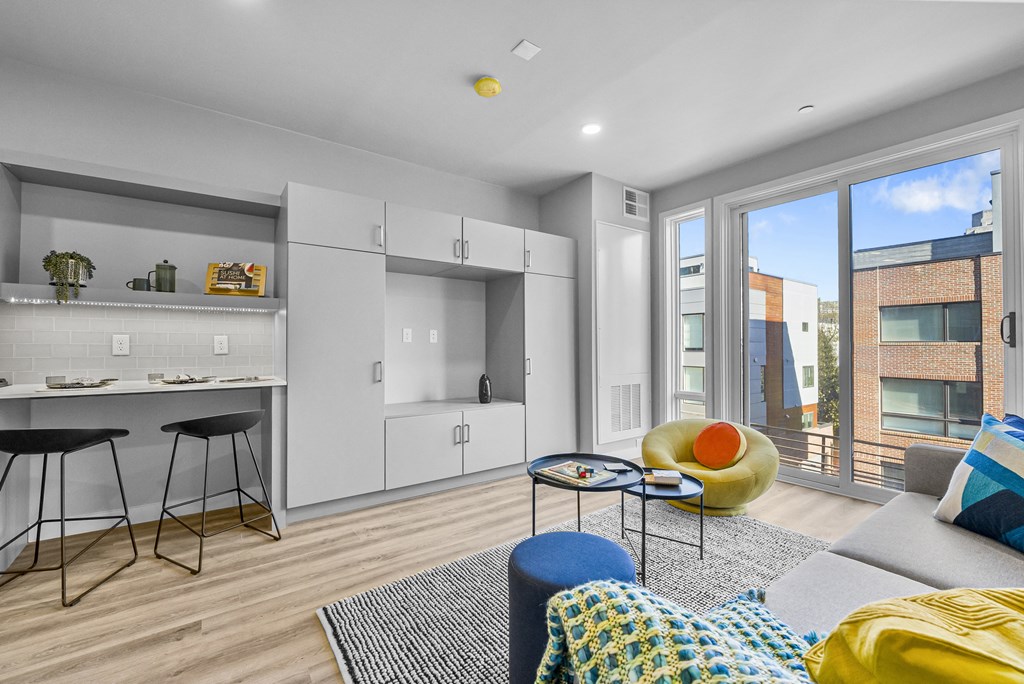 a kitchen and living room with white cabinetry and a large window
